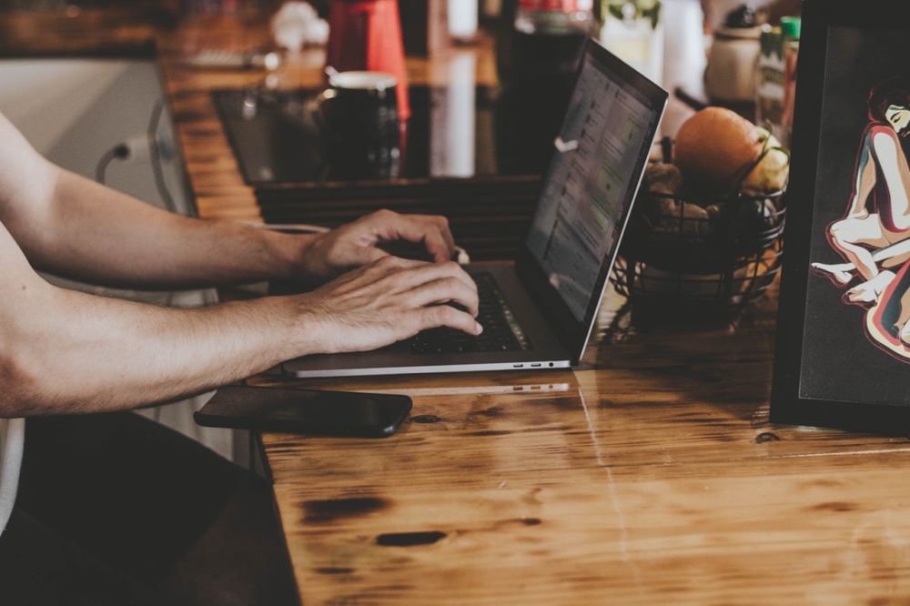 person in front of laptop on brown wooden table 2115217