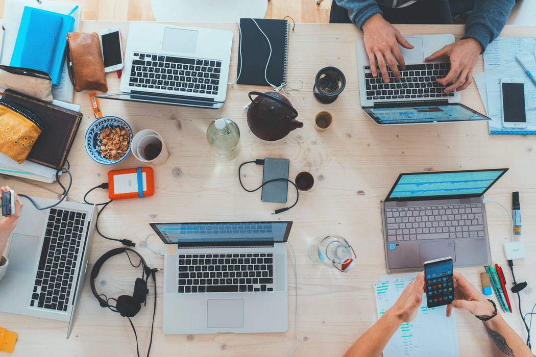 A top-down view of a workspace with laptops, a smartphone, and various items on a table