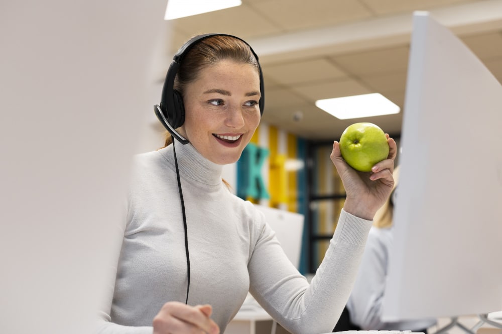 smiley woman having apple while working call center