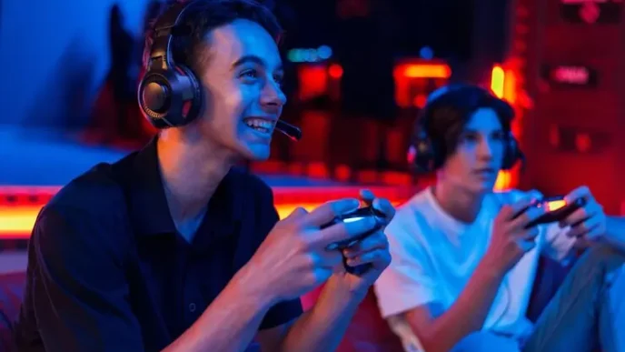 two teen friends headphones are playing game console using gamepads smiling 1268 25912