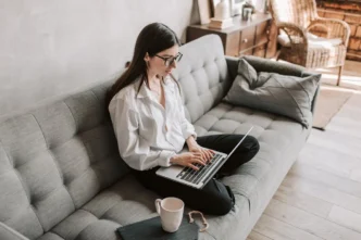 A woman sitting on a couch, using her laptop