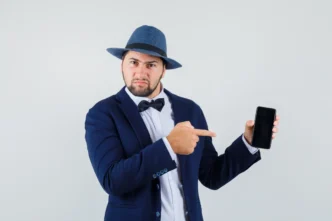 young man suit hat pointing mobile phone looking discontent front view